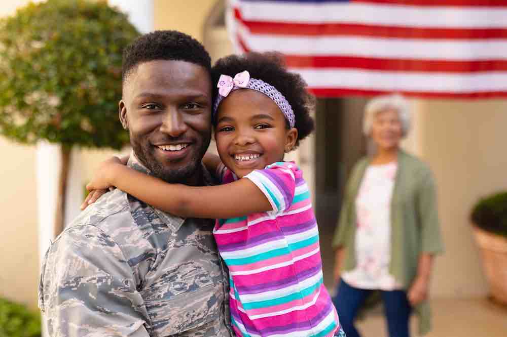 Portrait-of-happy-African-American-daughter-hugging-army-soldier.
