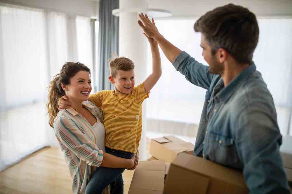 Happy family with children and moving boxes after using packing and moving services.
