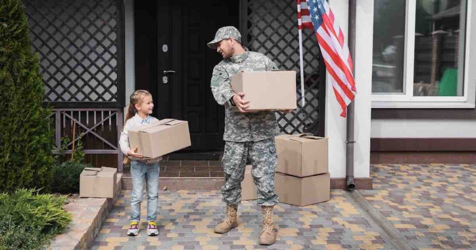 Father in military uniform and daughter holding cardboard boxes.